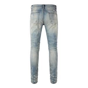 Detail of light blue washed denim with white paint splatter and distressed cat whisker whiskers
