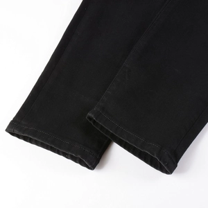 Close-up of black denim pants hem featuring precise double-needle stitching and twill texture