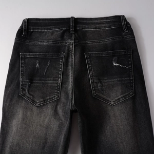 Détails des poches arrière sur jean noir ajusté avec déchirures et effet délavé