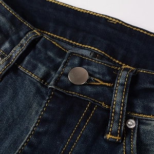 Close-up of men's slim denim jeans showing waist button and gold contrast stitching