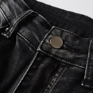 Détail macro du jean slim noir pour homme avec bouton métallique et coutures précises