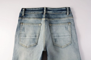 Detail view of washed light blue denim jeans showing back pockets with distressed texture
