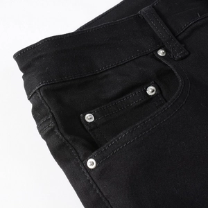 Detailed macro shot of black denim jeans waist pocket with silver metal rivet studs