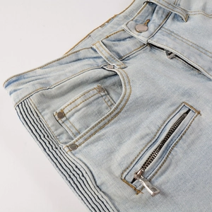 Close-up of light blue biker jeans with accordion pleated texture and metal zippers