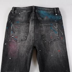 Detail view of the back pockets and colorful paint splatter on dark grey denim jeans