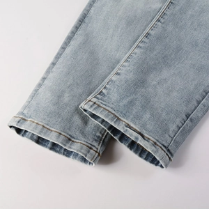 Close-up of light blue men's denim jeans hem with premium stitching and washed texture