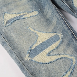 Slim fit light blue washed jeans featuring distressed patches and frayed embroidery details