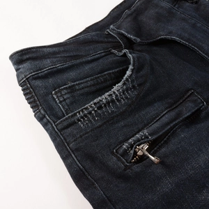Detailed close-up of dark blue biker jeans featuring distressed pocket and zipper details