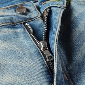 Detail shot of men's slim fit jeans showing silver metal zipper and yellow stitching