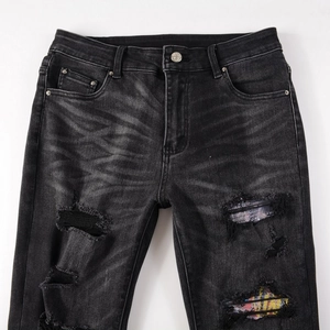 Detail showing charcoal grey slim fit jeans with distressed rips and colorful patches