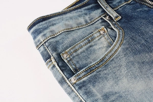 Close-up of dark blue washed denim jeans featuring metal rivets and orange contrast stitching
