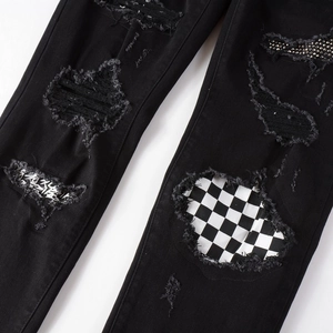 Slim fit black distressed jeans with checkerboard patches and sparkling rhinestone details