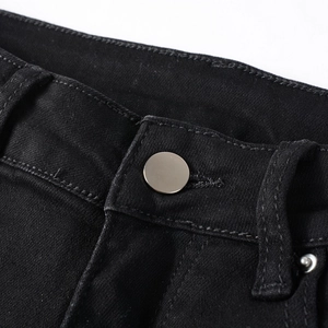 Close-up of black denim jeans featuring metal button closure and belt loop details