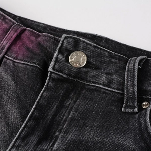 Detail of dark grey ripped jeans showing metal button and purple gradient wash effects