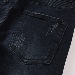 Detail of dark blue biker jeans featuring ribbed moto panels and reinforced stitching
