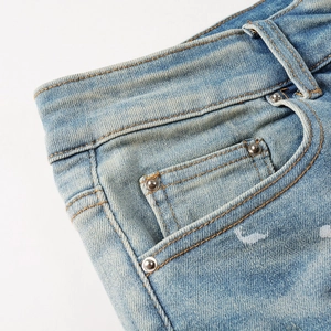 Detailed close-up of light blue denim fabric texture with silver rivets and belt loops