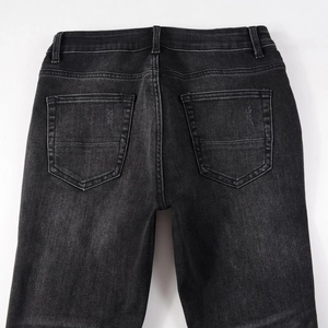 Detail view of the back pockets and washed texture on these slim fit black denim jeans