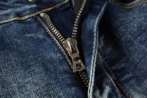 Detail of high-quality metal zipper and yellow stitching on blue washed denim jeans