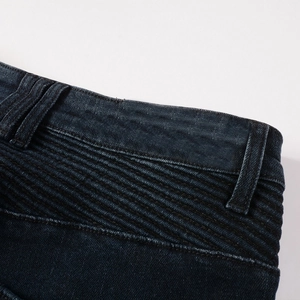 Macro view of dark blue motorcycle jeans showing quilted stitching and washed denim texture