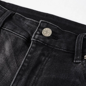 Detail of waist area on black slim fit jeans with metal button and precise stitching