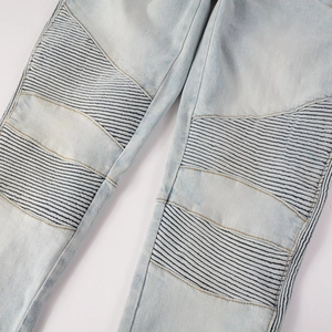 Detail of moto-style ribbed pleats and light wash texture on slim fit biker jeans
