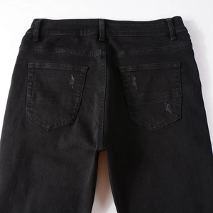 Detail of back pocket with distressed rip and waist belt loops on black denim jeans