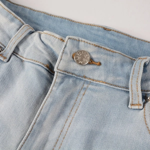 Makroaufnahme der hellblauen Jeans-Taille mit Silberknopf und orangefarbenen Kontrastnähten