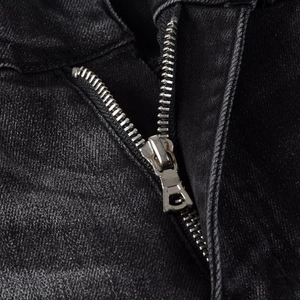 Detail shot of a high-quality silver metal zipper on black washed slim fit jeans