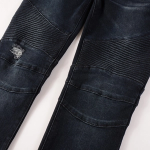 Detailed macro view of motorcycle panels and distressed hole on dark blue denim jeans