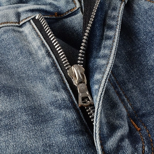 Detailed macro view of high-quality metal zipper and washed blue denim texture on men's jeans