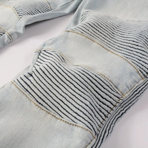 Detailed macro view of pleated ribbed panels and yellow stitching on light blue biker jeans