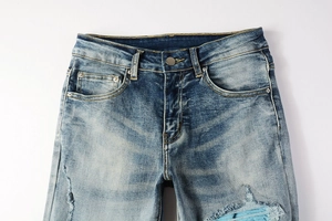 Detailed macro view of light blue distressed denim jeans with vintage wash and ripped patches