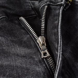Detail of high-quality silver metal zipper on distressed black slim fit men's jeans