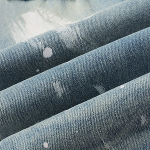 Detailed macro view of blue denim fabric with white paint splatter and twill texture
