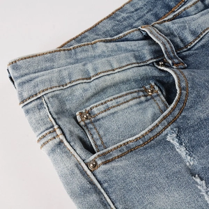 Detailed close-up of light blue men's jeans with orange contrast stitching and rivets