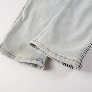 Close-up of slim fit denim jeans hem showing light blue wash and orange contrast stitching