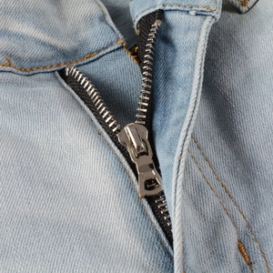 Nahaufnahme von Metallreißverschluss und gelben Nähten an hellblauen Denim-Jeans