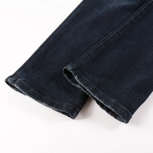 Close-up of slim-fit denim jeans featuring raw distressed hems and retro frayed edges
