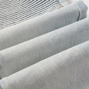 Close-up of distressed light blue denim texture with ribbed stitching and twill weave