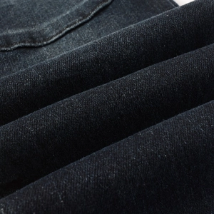 Detail shot of navy denim fabric showing twill weave and reinforced stitching on jeans