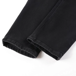 Detailed close-up of the double-stitched hem on black slim fit distressed denim jeans