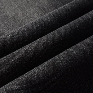Détail du tissu denim noir montrant la texture épaisse et le motif de tissage en sergé