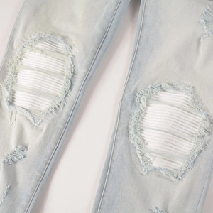 Detail der hellblauen Jeans mit weißen Ripp-Knieflicken und ausgefransten Kanten