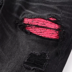 Gros plan sur un jean noir avec des trous déchirés et des détails de patch rose vif