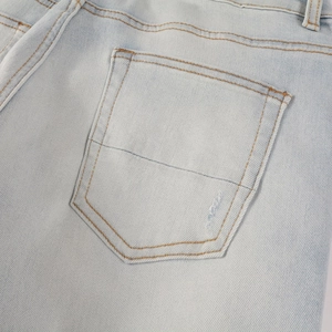 Makroaufnahme der Gesäßtasche an hellblauen Distressed-Jeans mit braunen Kontrastnähten