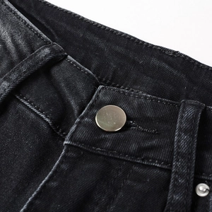 Macro detail of high-quality black denim waist with matte silver button and neat stitching