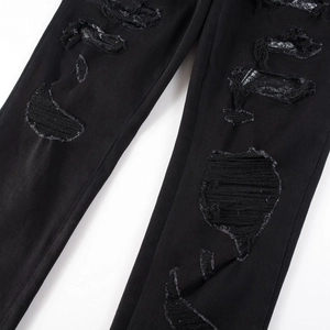 Men's distressed black jeans with embroidered cobra patches and textured ripped details