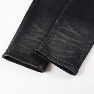 Detailed view of tapered jeans cuffs featuring whiskers wash and double-needle stitching