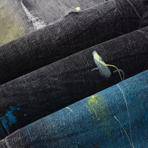 Macro shot of charcoal grey denim fabric with vibrant street style graffiti paint splatter