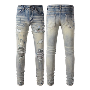 Detail of light wash slim jeans with ripped knees, paint splatters and striped patches